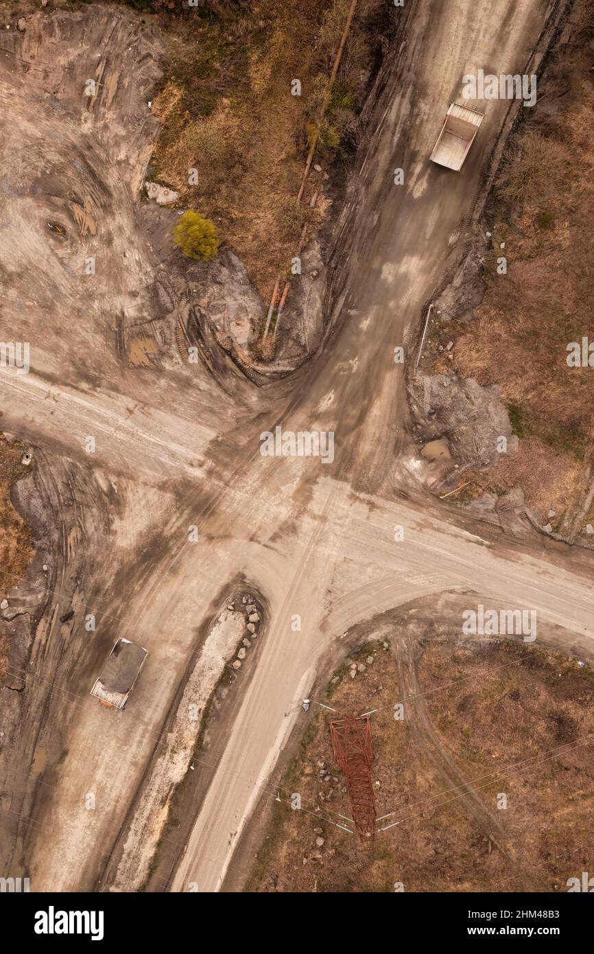 Dump trucks on granite quarry mining facility aerial. Trucks loaded with granite rocks on a road from a drone Stock Photo