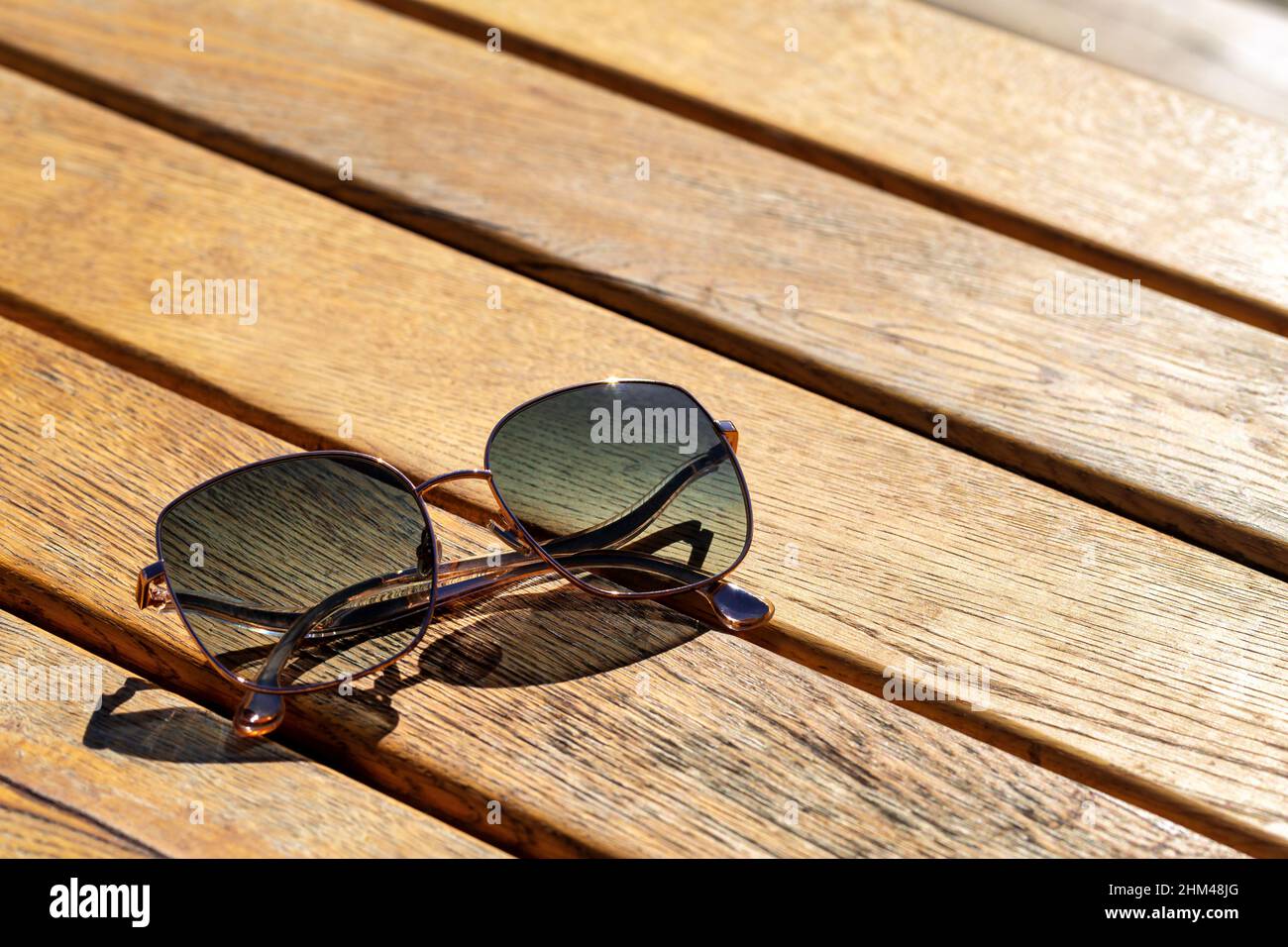 Trendy sunglasses on wooden table. Outdoors closeup in bright sun Stock Photo