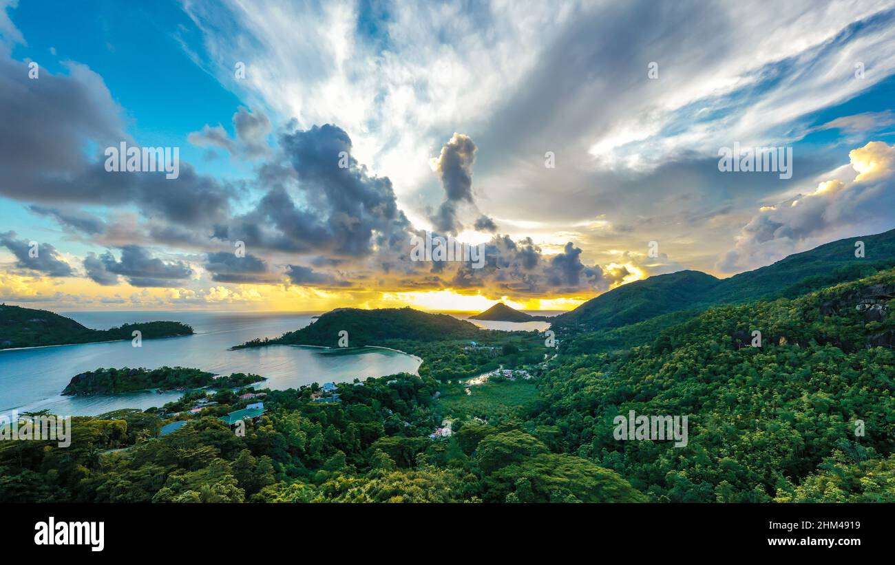 Mahe Island coast high resolution drone panorama during sunset, with dramatic sky, clouds, lush tropical forest and small islands around. Stock Photo