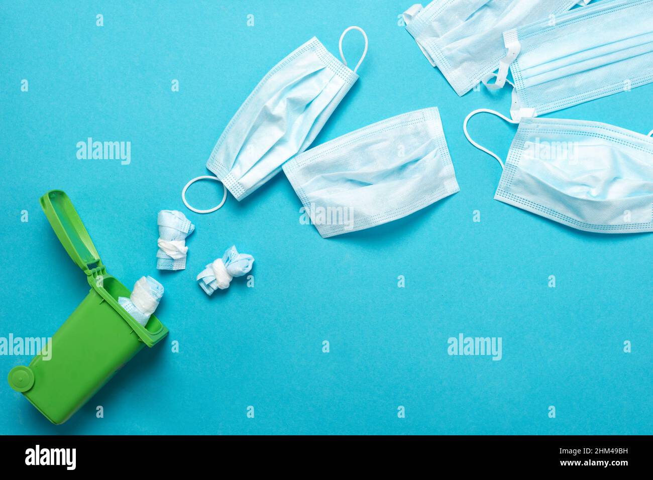 Disposal of a medical mask in a green container for recycling on a blue ...