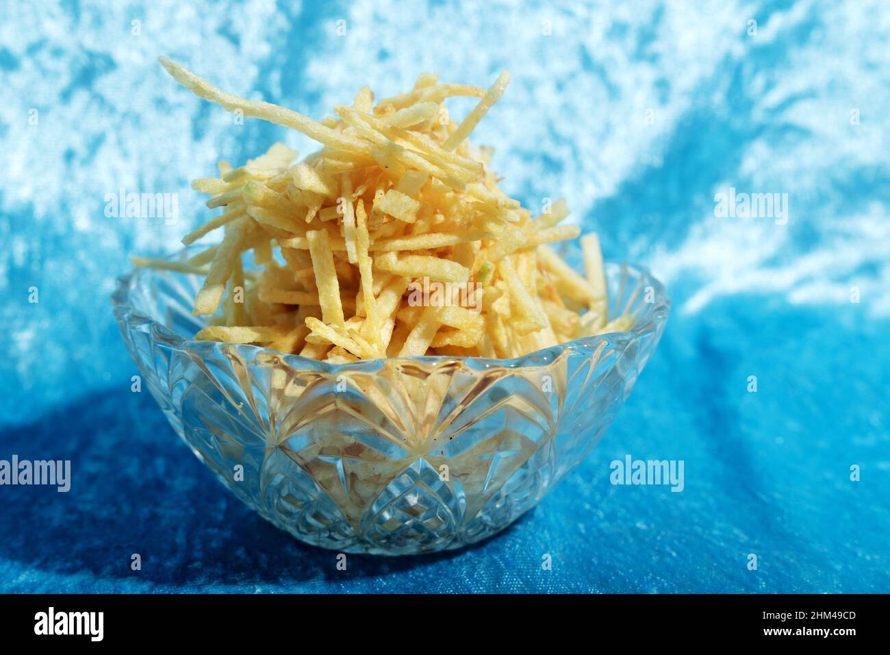 potato chips in elegant vintage glass bowl on light blue cloth Stock Photo