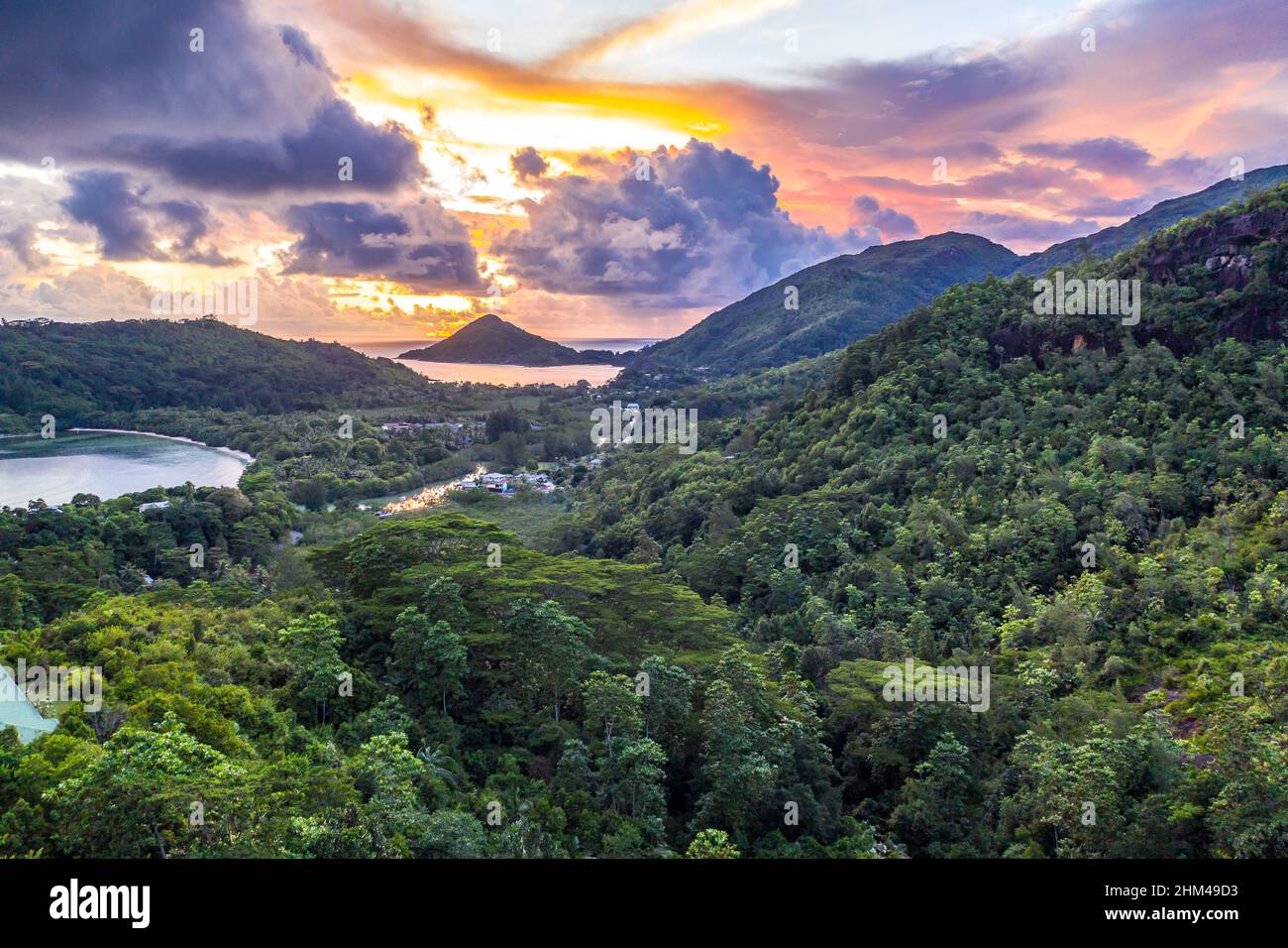 Mahe Island coast drone sunset landscape with dramatic pink sky, clouds, lush tropical forest and small islands around. Stock Photo