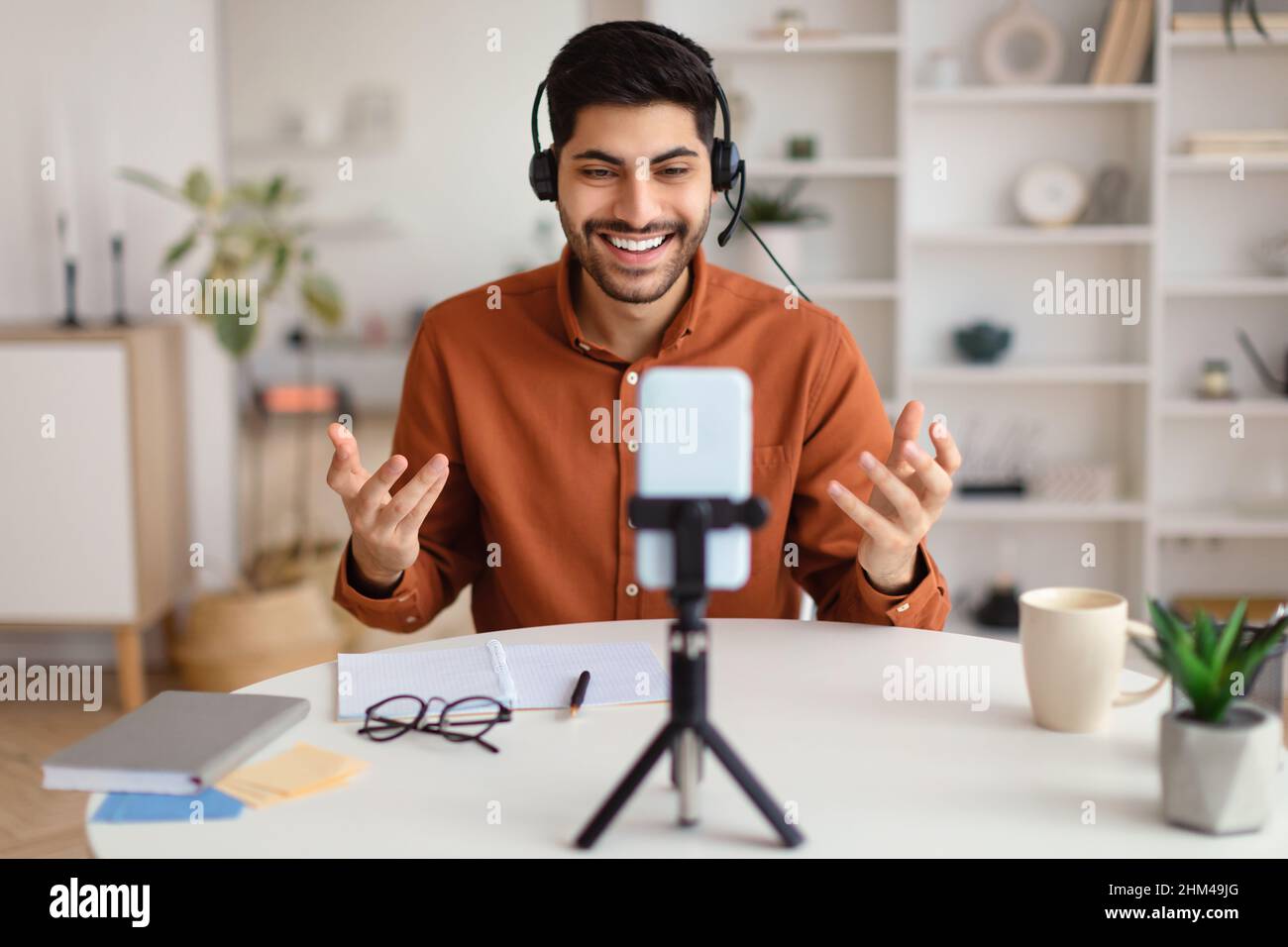 Arab man having videocall using cellphone on tripod and talking Stock Photo