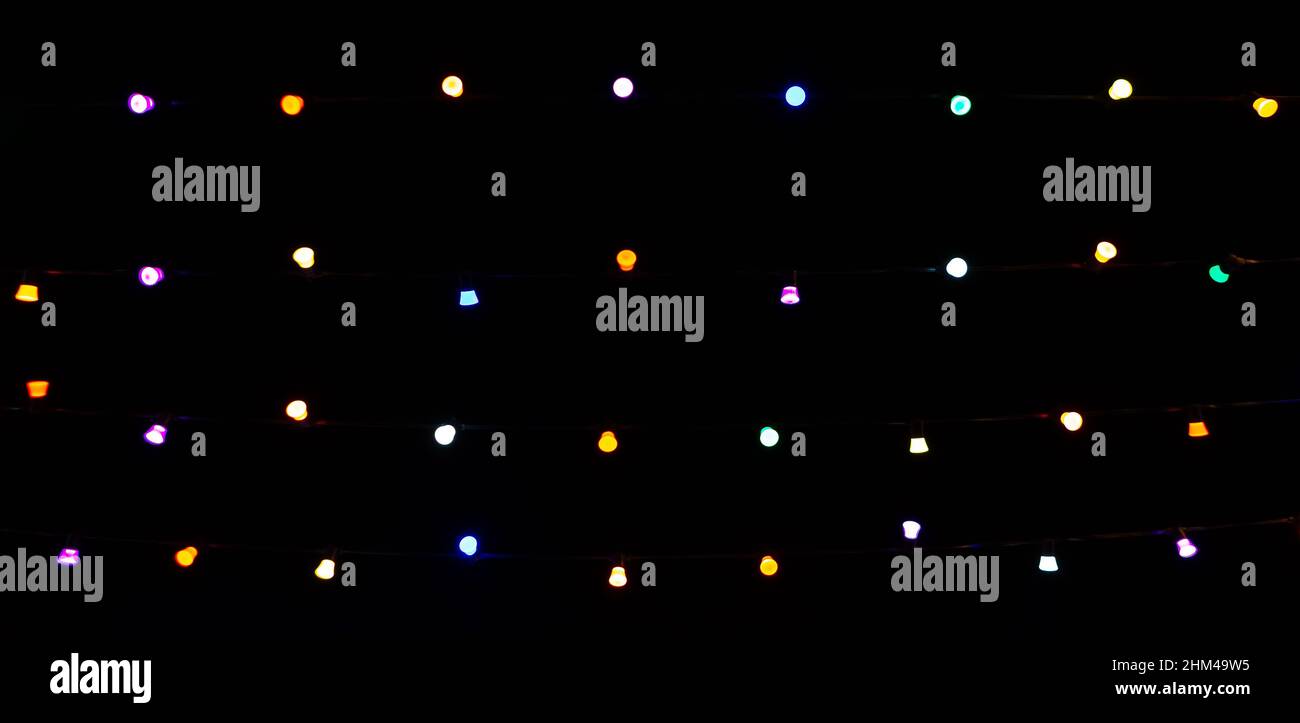 Multicolored light bulbs on dark hight sky background. Blurred focus. Banner. Stock Photo