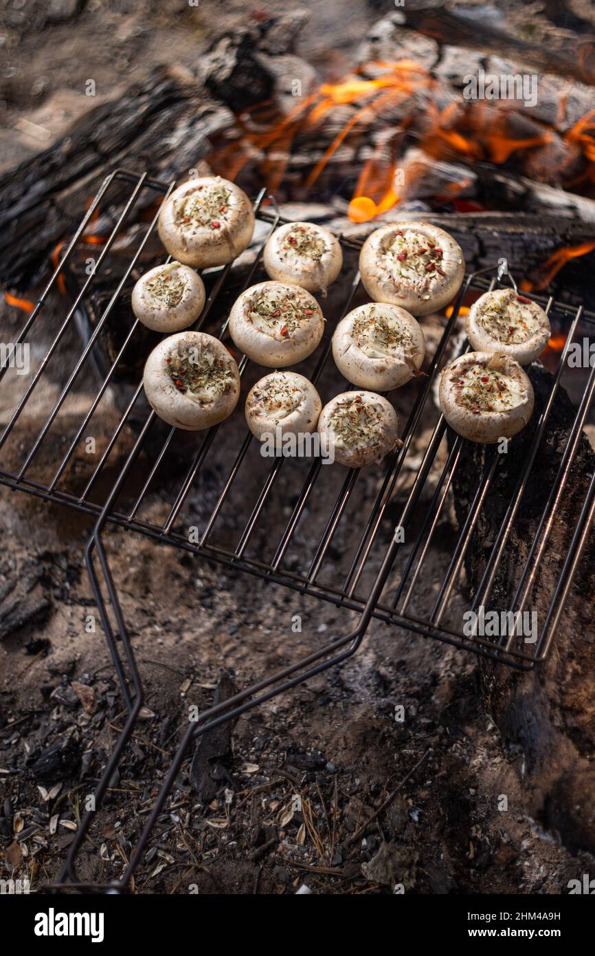 Champignon mushrooms stuffed with cheese and spices grilled on a campfire Stock Photo