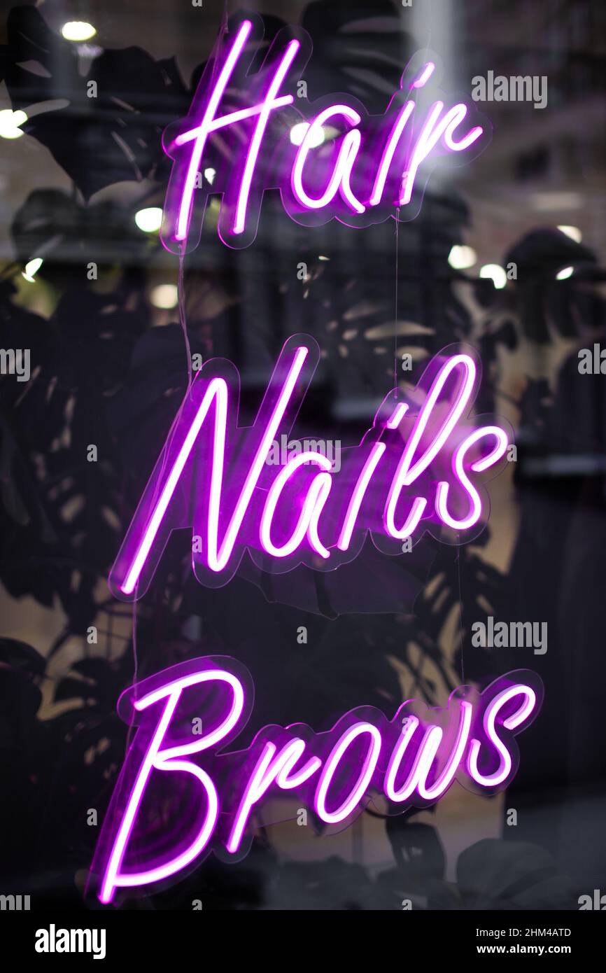 Beauty salon neon sign hair, nails, brows. Hair salon, manicure cabinet, eyebrows correction. Shallow depth of field Stock Photo