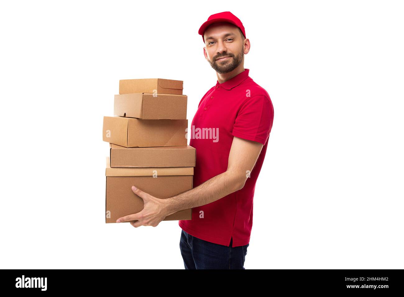 The courier of the delivery service stands in a half-turn and holds in his hands ah uphill cardboard boxes Stock Photo