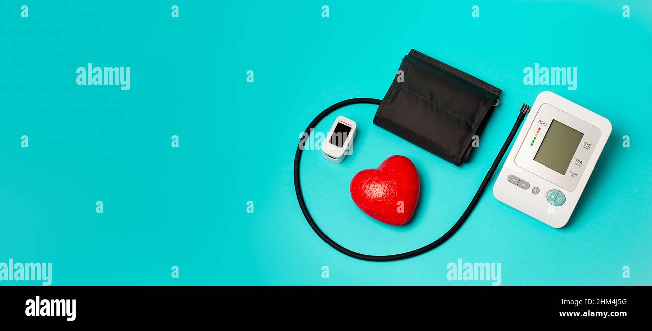 On a medical background, an automatic tonometer for measuring pressure, a pulse oximeter, a red heart. Measurement of oxygen level in the blood. Satur Stock Photo