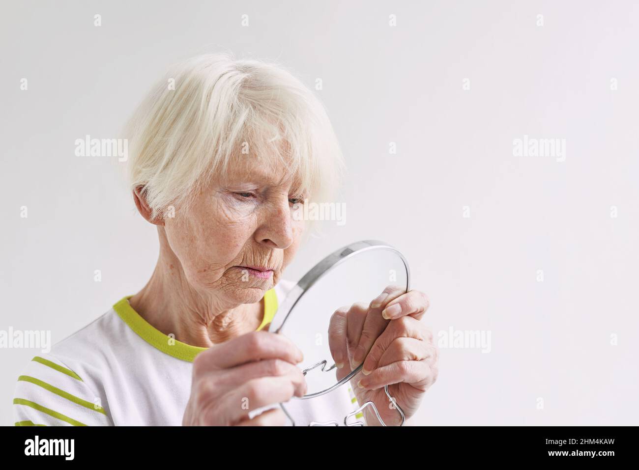 senior sad woman looking at herself in mirror. Age, time, skin care concept Stock Photo