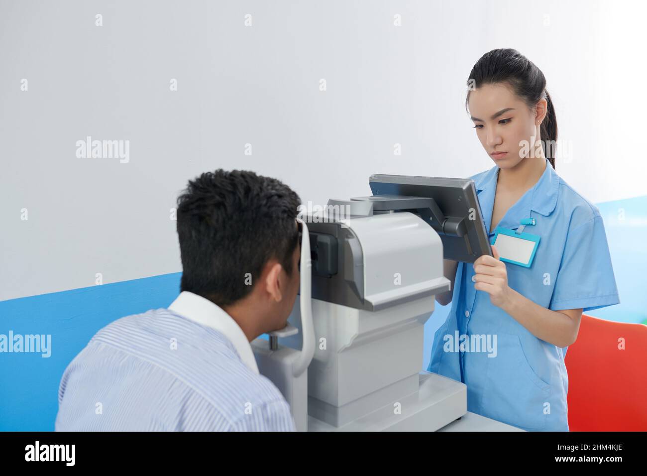 Serious young optometrist checking data on touchscreen when patient ...