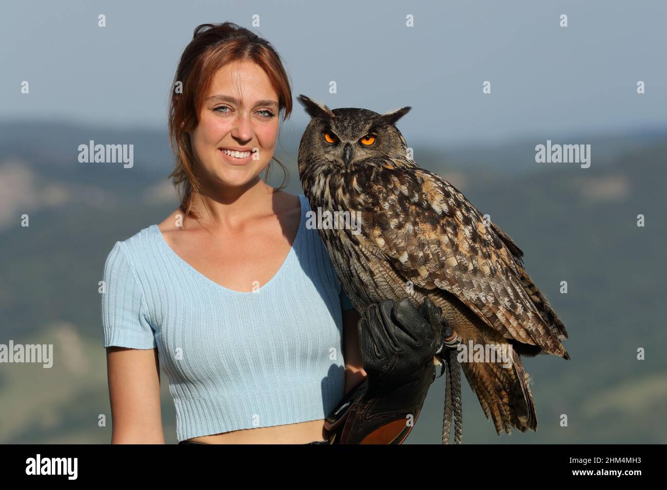Happy falconer holding a eagle owl looking at you smiling at camera Stock Photo