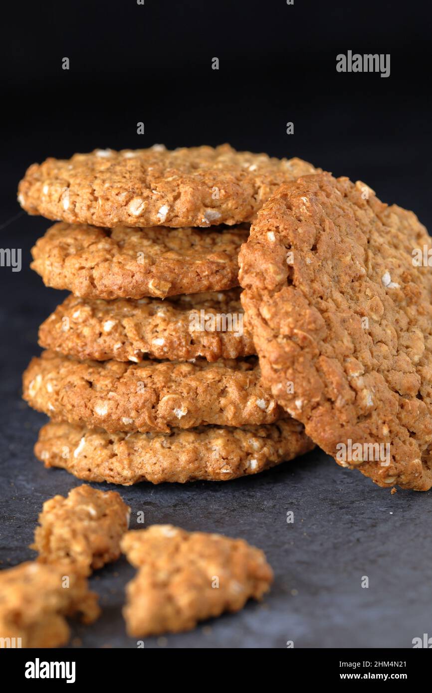 Homemade crunchy texture organic oat gluten free biscuit cookies stacked in a pile on a dark background Stock Photo
