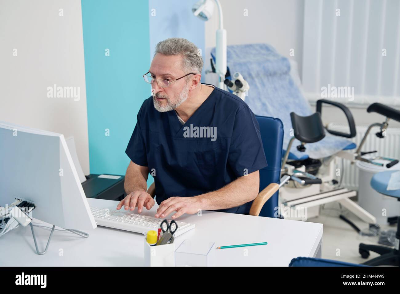 Physician working on desktop computer in his office Stock Photo