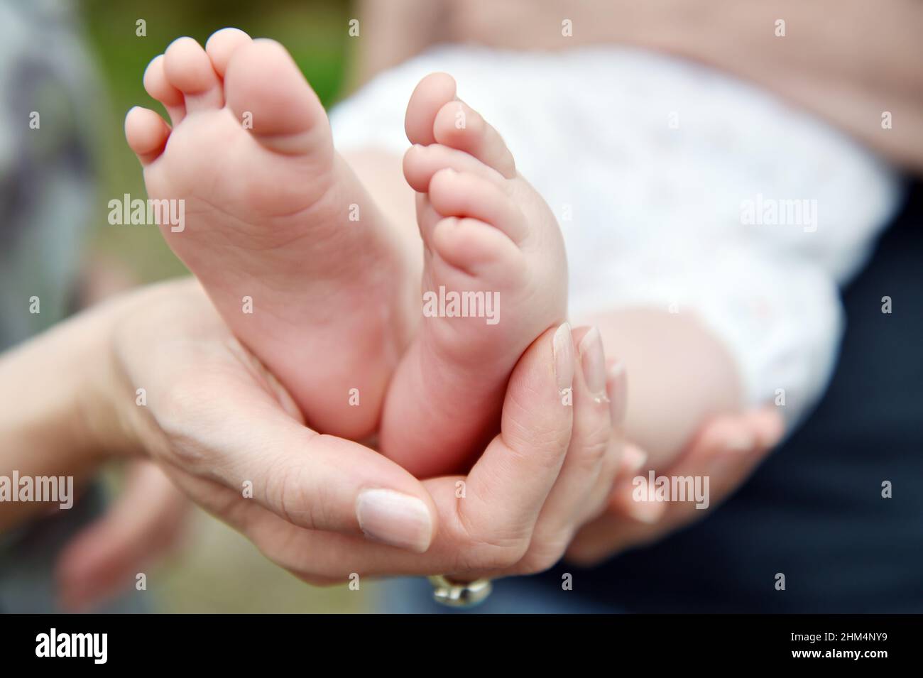 Baby feet, a parent cups her new-born baby feet in her hand. Stock Photo
