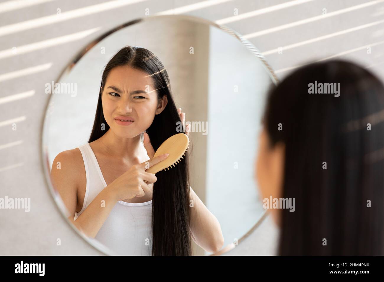 Irritated chinese woman having problem of her thick hair Stock Photo