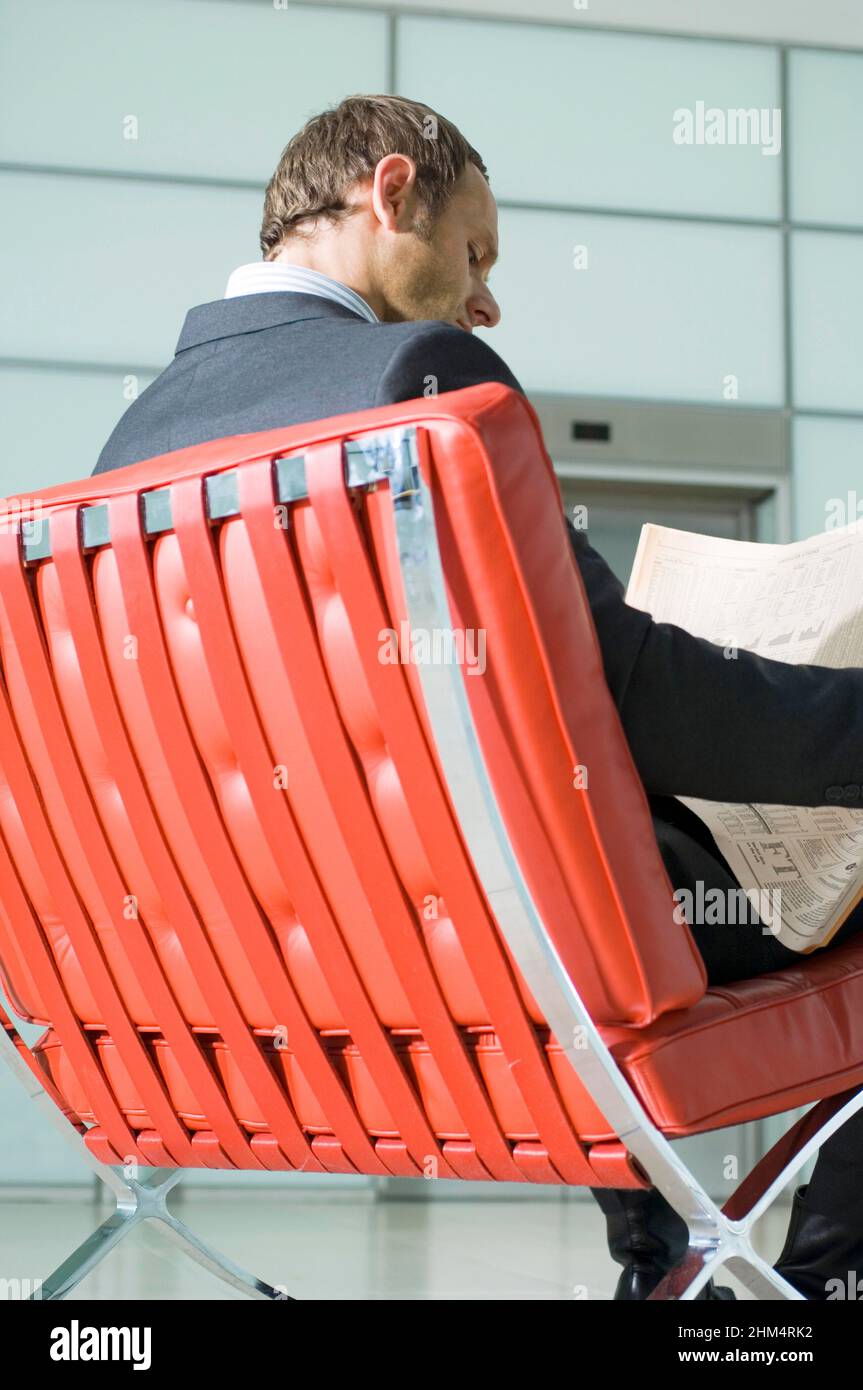 Rear View Of A Businessman Sitting On A Chair And Reading A Newspaper, Credit:Photoshot Creative / Stuart Cox / Avalon Stock Photo
