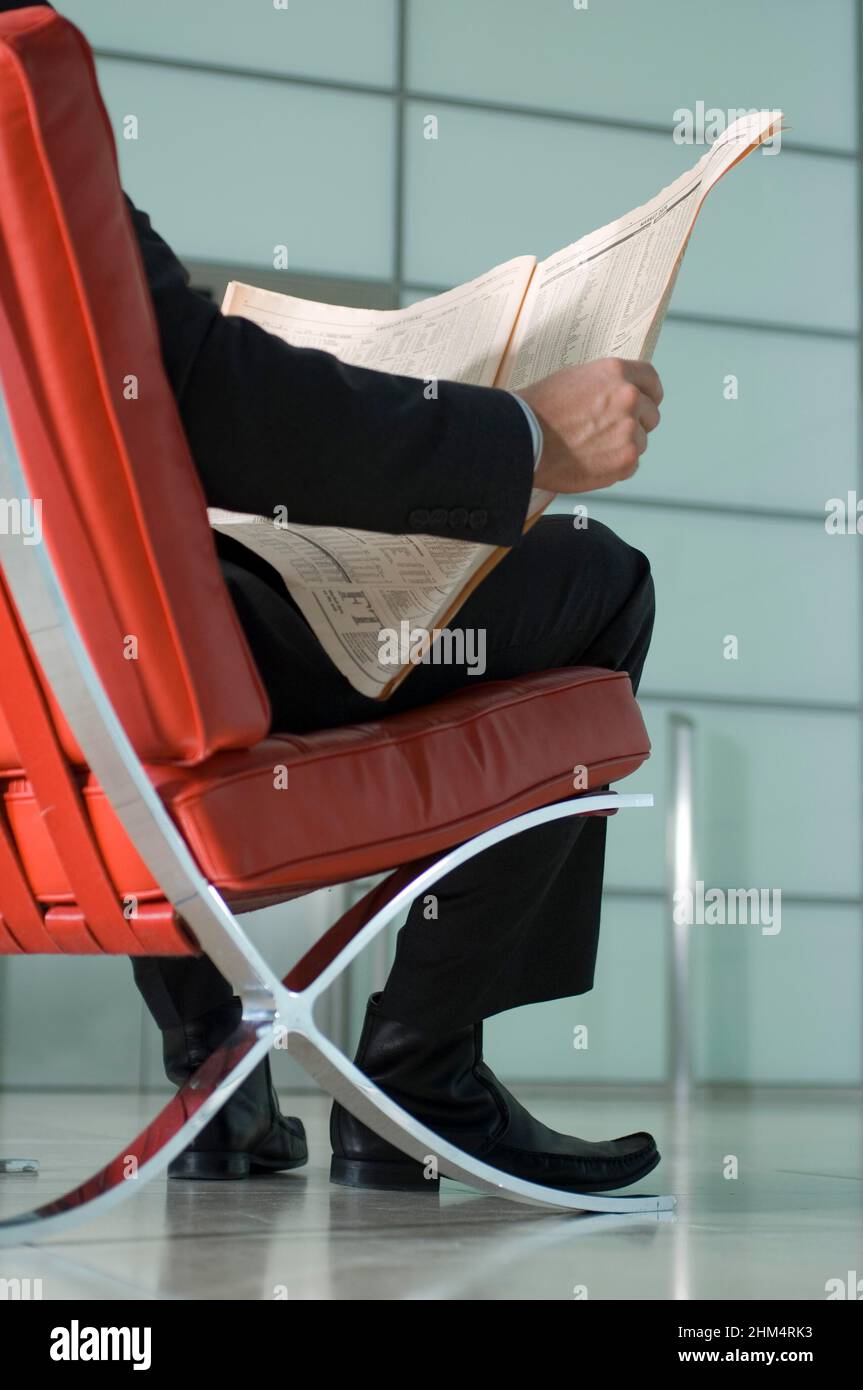Rear View Of A Businessman Sitting On A Chair And Holding A Newspaper, Credit:Photoshot Creative / Stuart Cox / Avalon Stock Photo