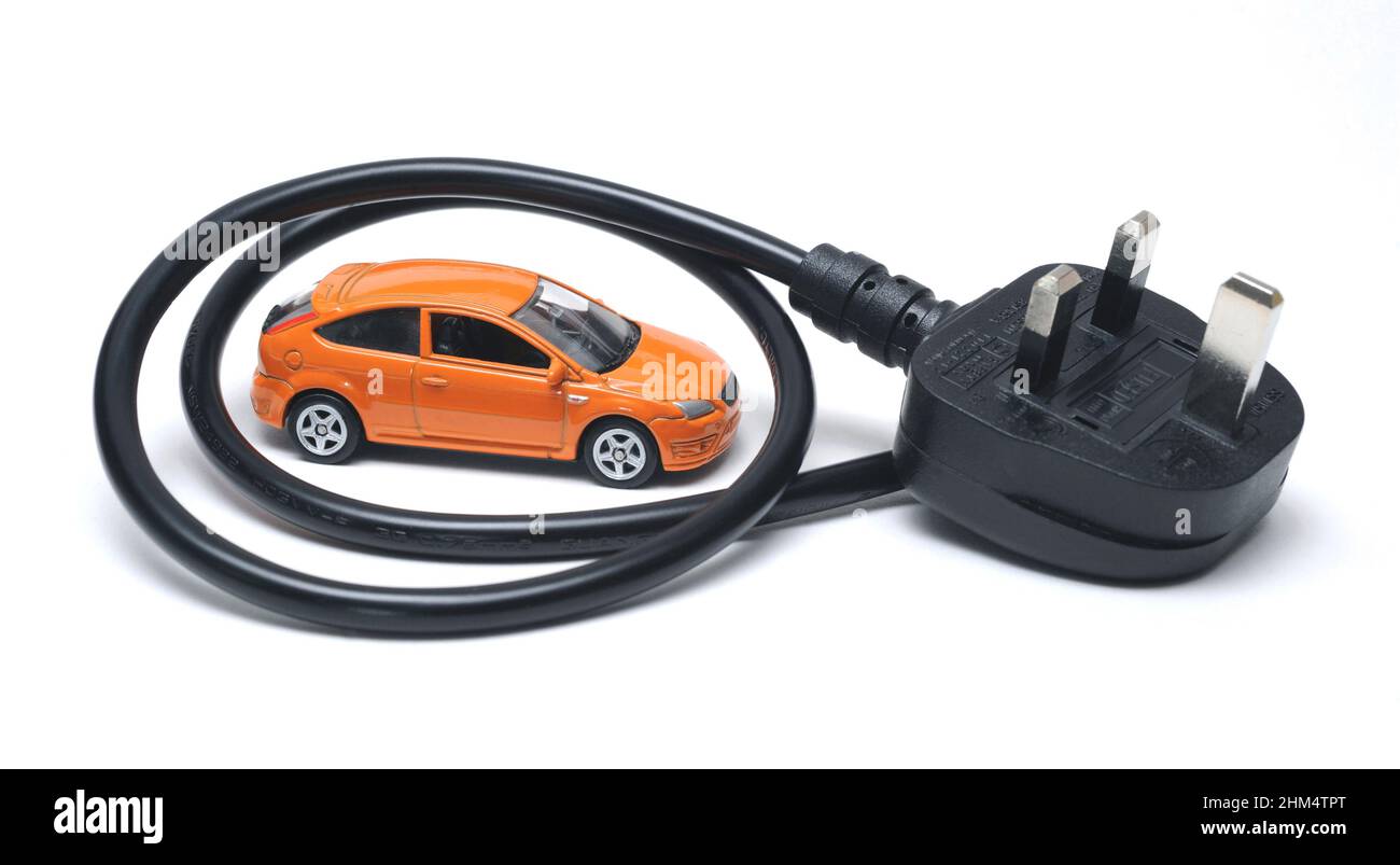 MODEL CAR WITH ELECTRIC PLUG AND LEAD RE ELECTRIC CARS EV EV'S SWITCHING TO CLEANER CARS THE ENVIRONMENT PETROL DIESEL ETC UK Stock Photo