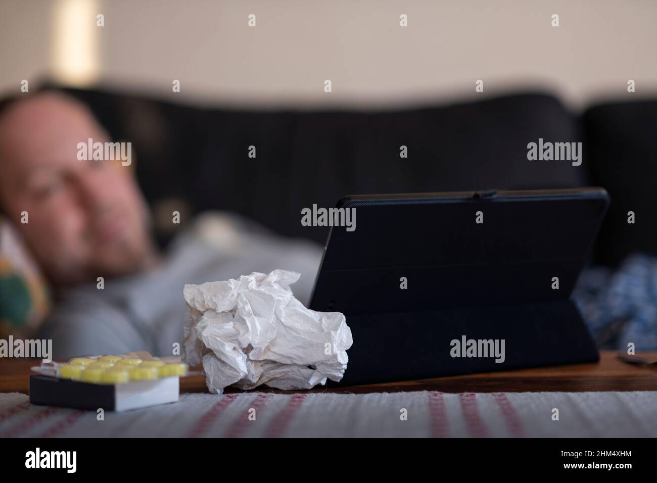Sick man lying at home and using digital tablet Stock Photo