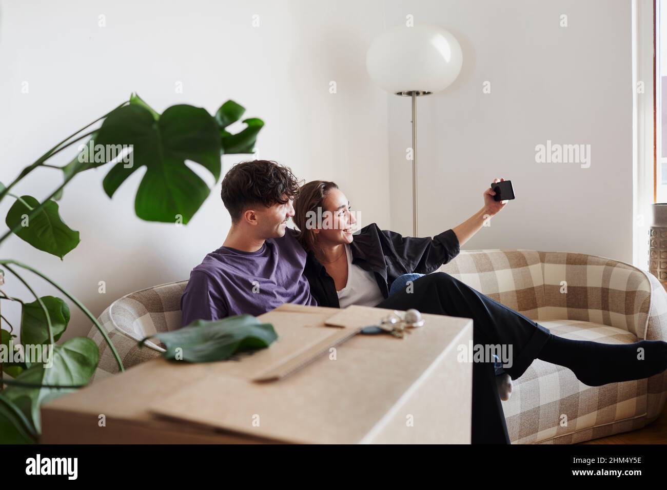 Young couple on sofa taking selfie Stock Photo
