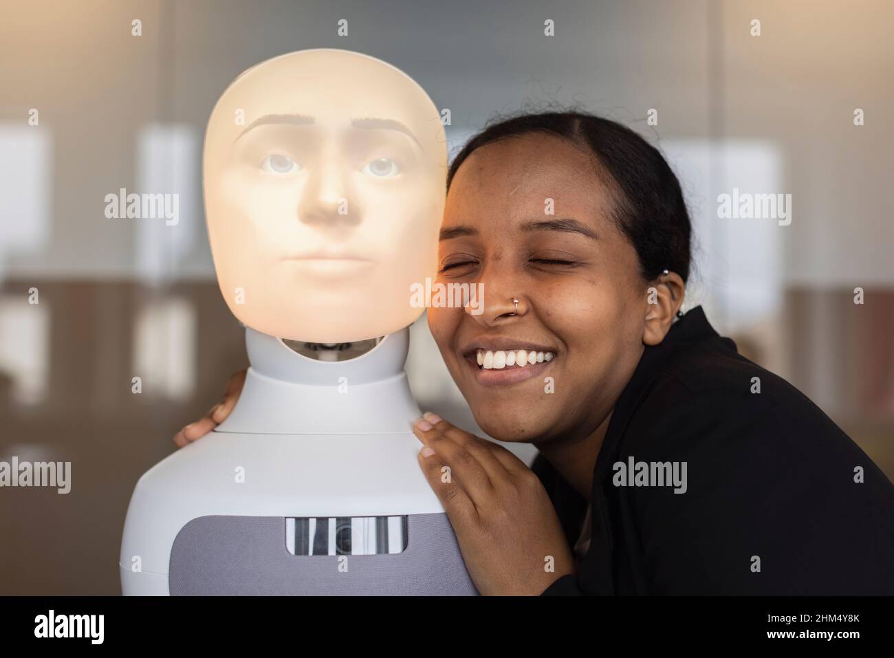 Smiling young woman with robot voice assistant Stock Photo