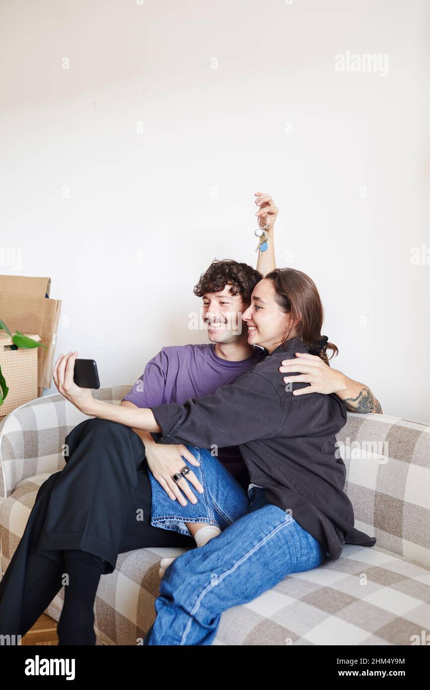 Young couple on sofa taking selfie Stock Photo