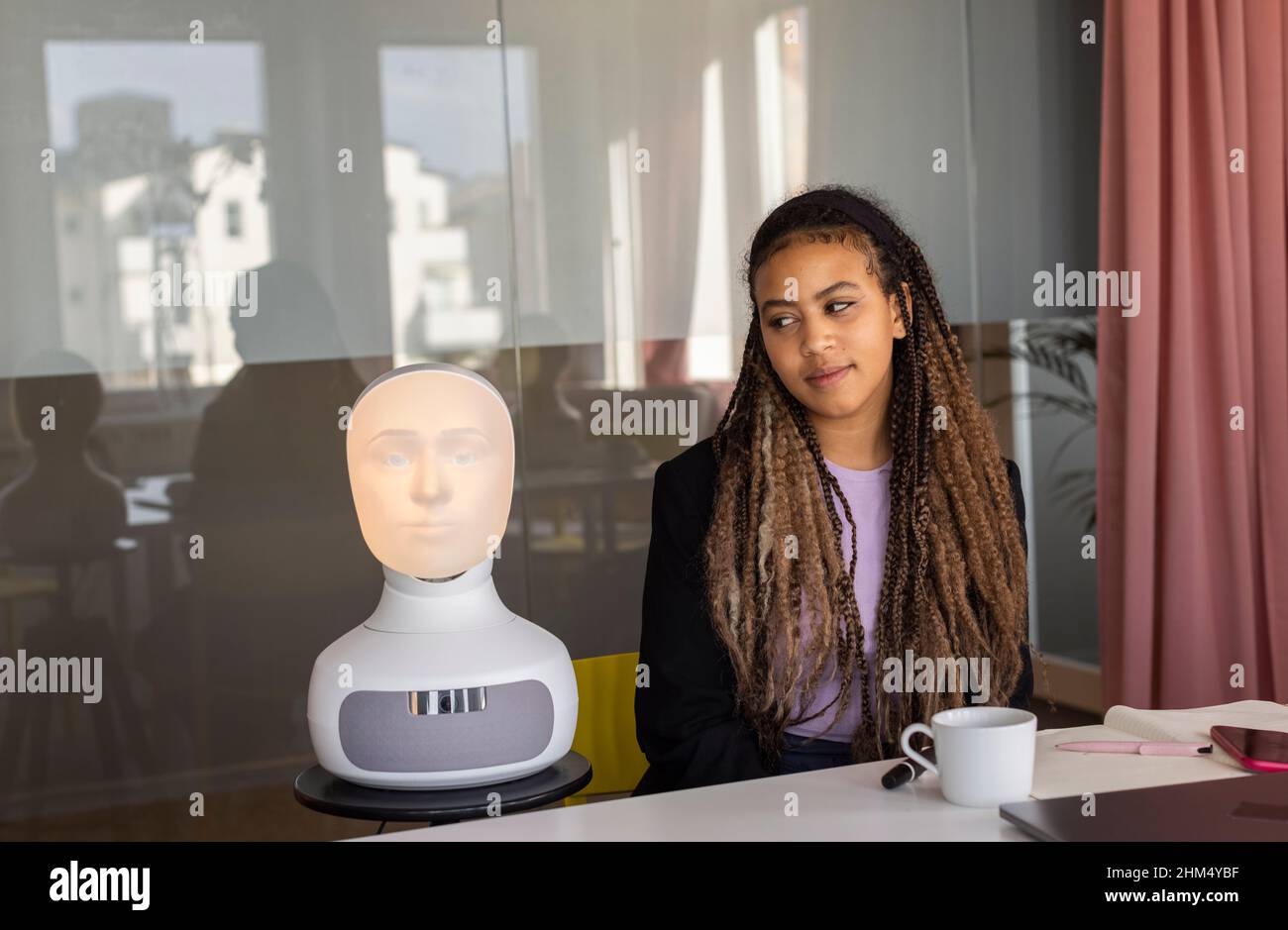 Businesswoman looking at robot voice assistant Stock Photo