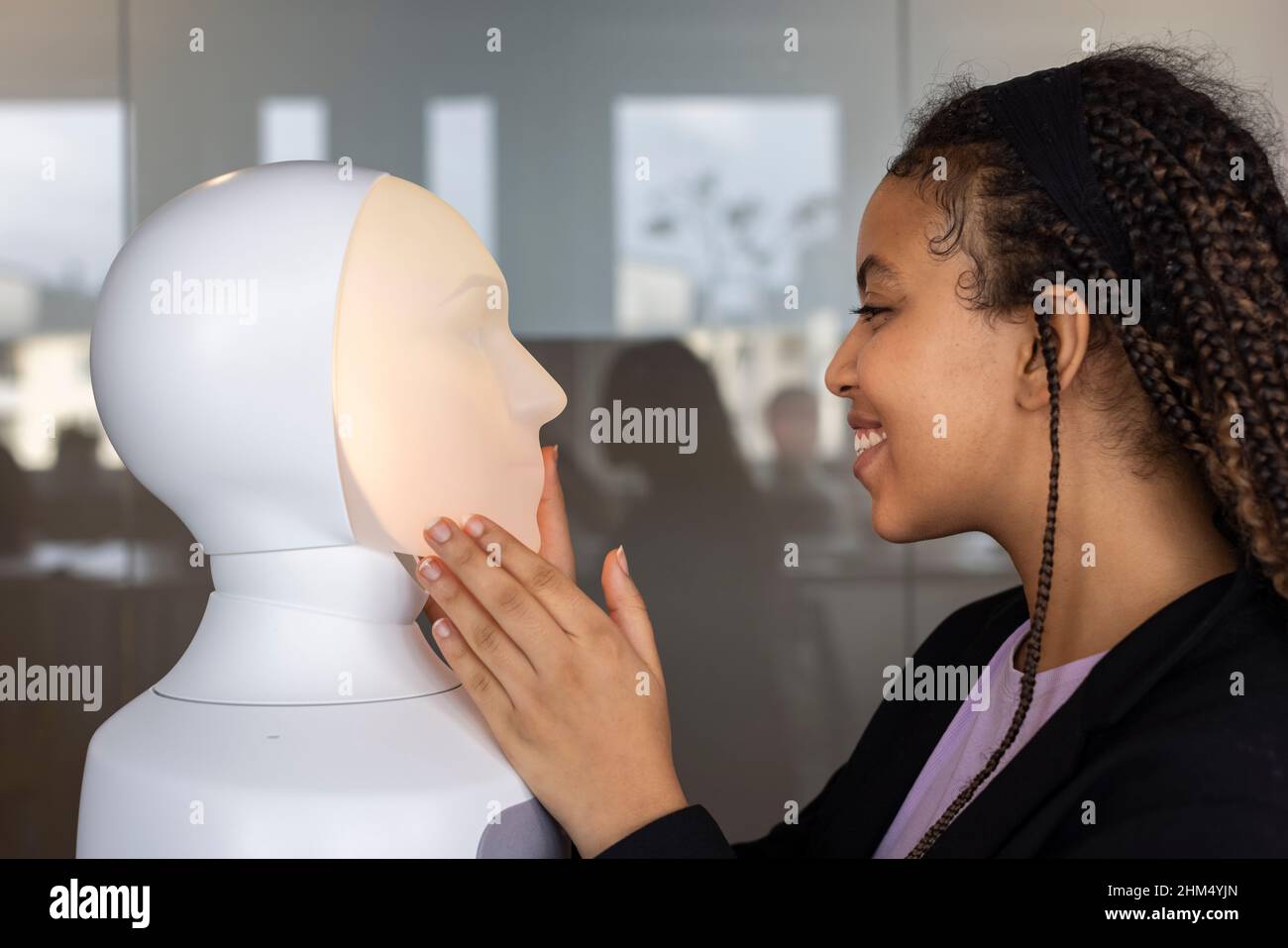 Smiling woman looking at robot voice assistant Stock Photo