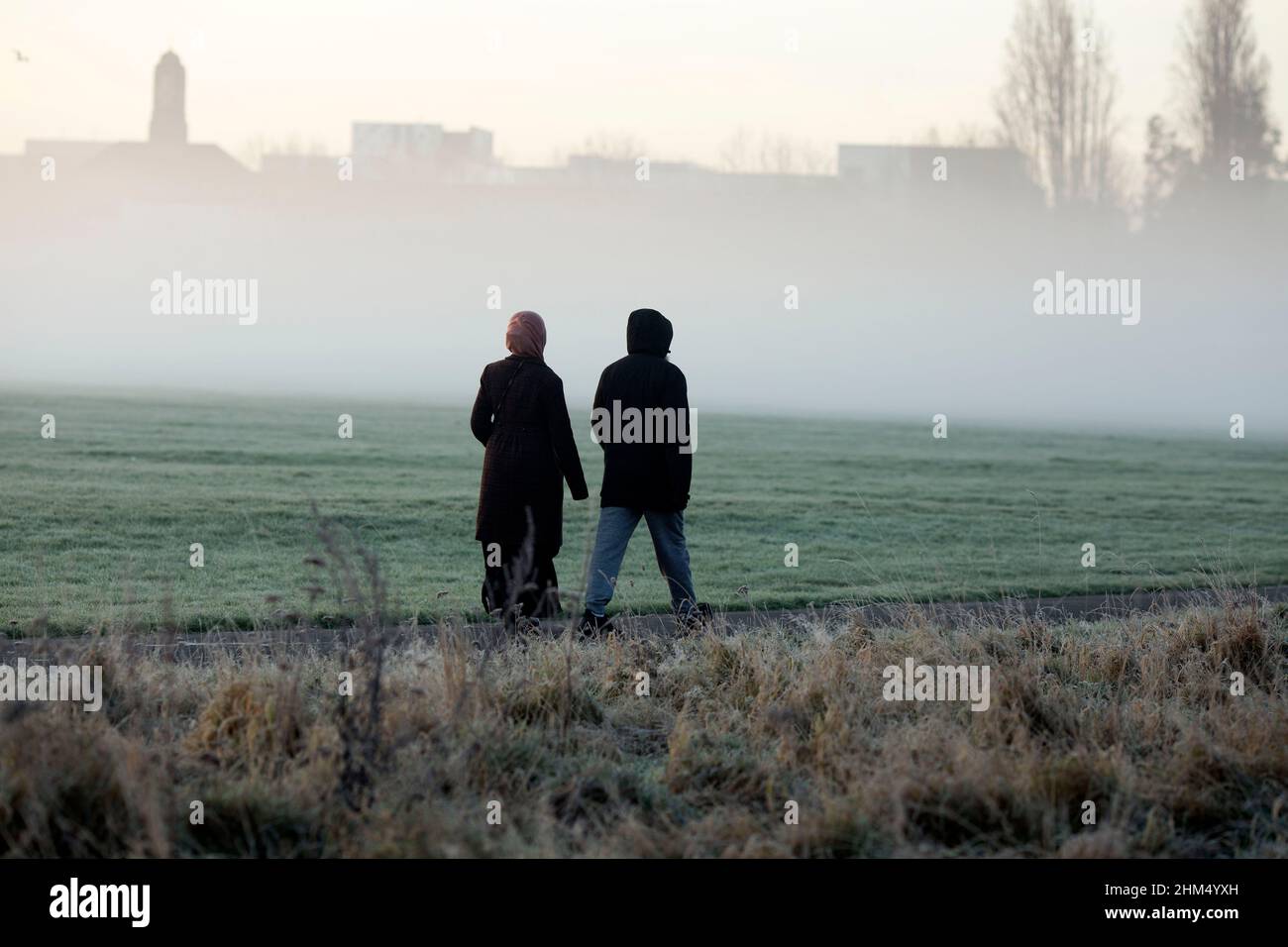 Pedestrians walk in a mistcovered park in Ilford, East London, in the
