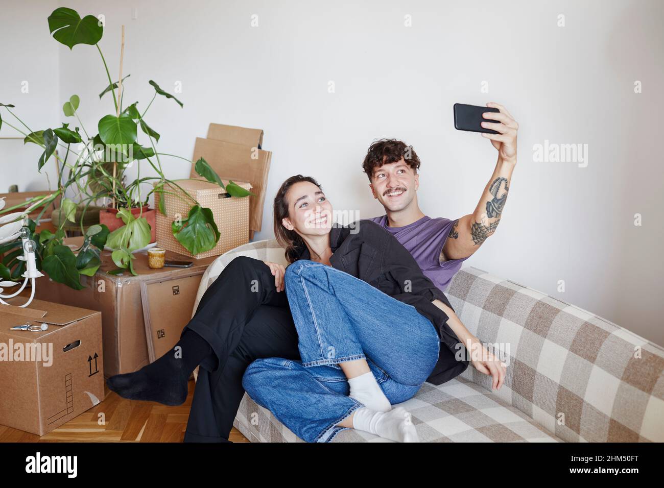 Young couple on sofa taking selfie Stock Photo