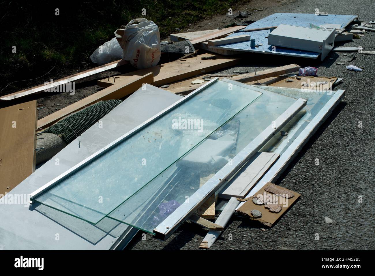 Close up of fly tipped household rubbish including glass, timber, wood and underlay Stock Photo