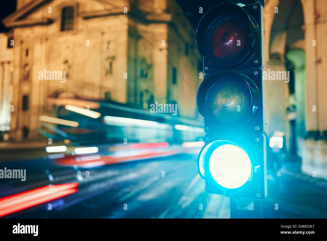Green on traffic light against tram and cars in blurred motion. Night scene of city street in Prague, Czech Republic. Stock Photo