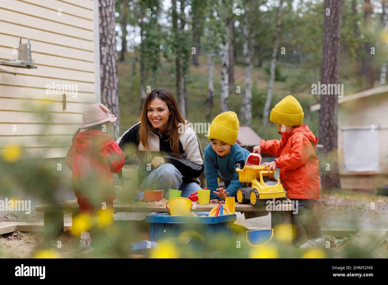 Mother playing with children in sandpit Stock Photo