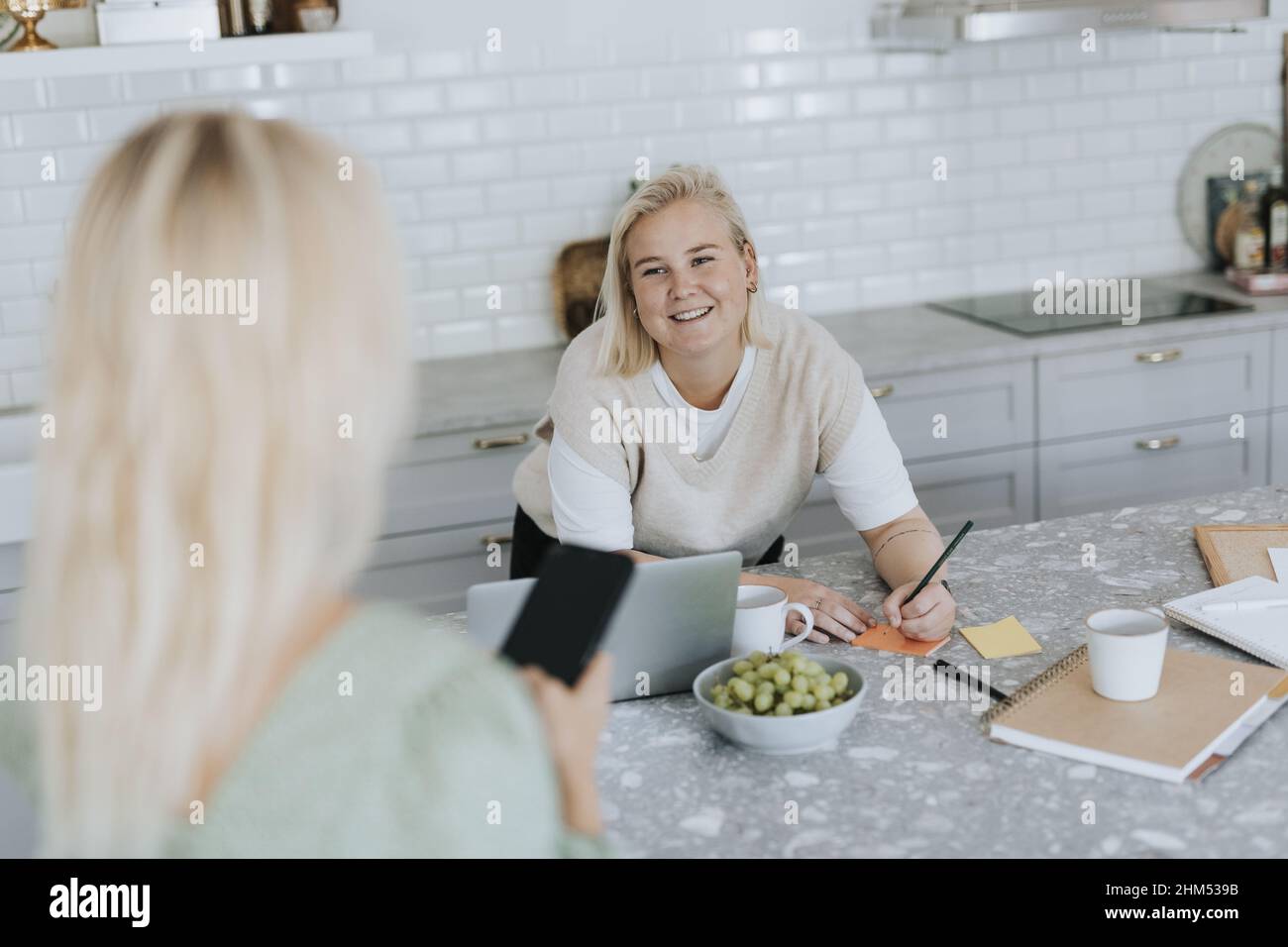 Smiling women talking in kitchen Stock Photo