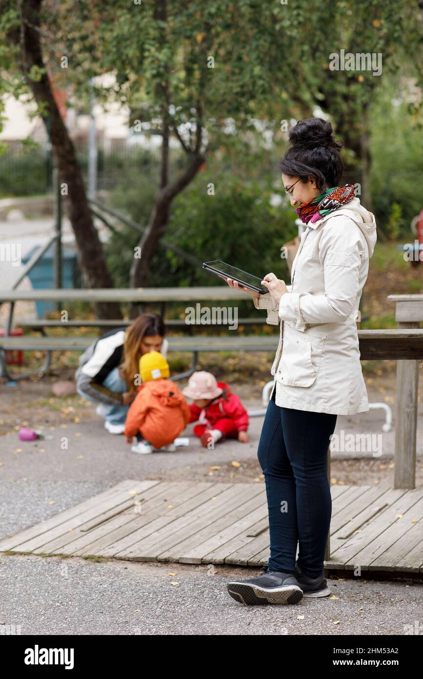 Woman at playground using digital tablet Stock Photo