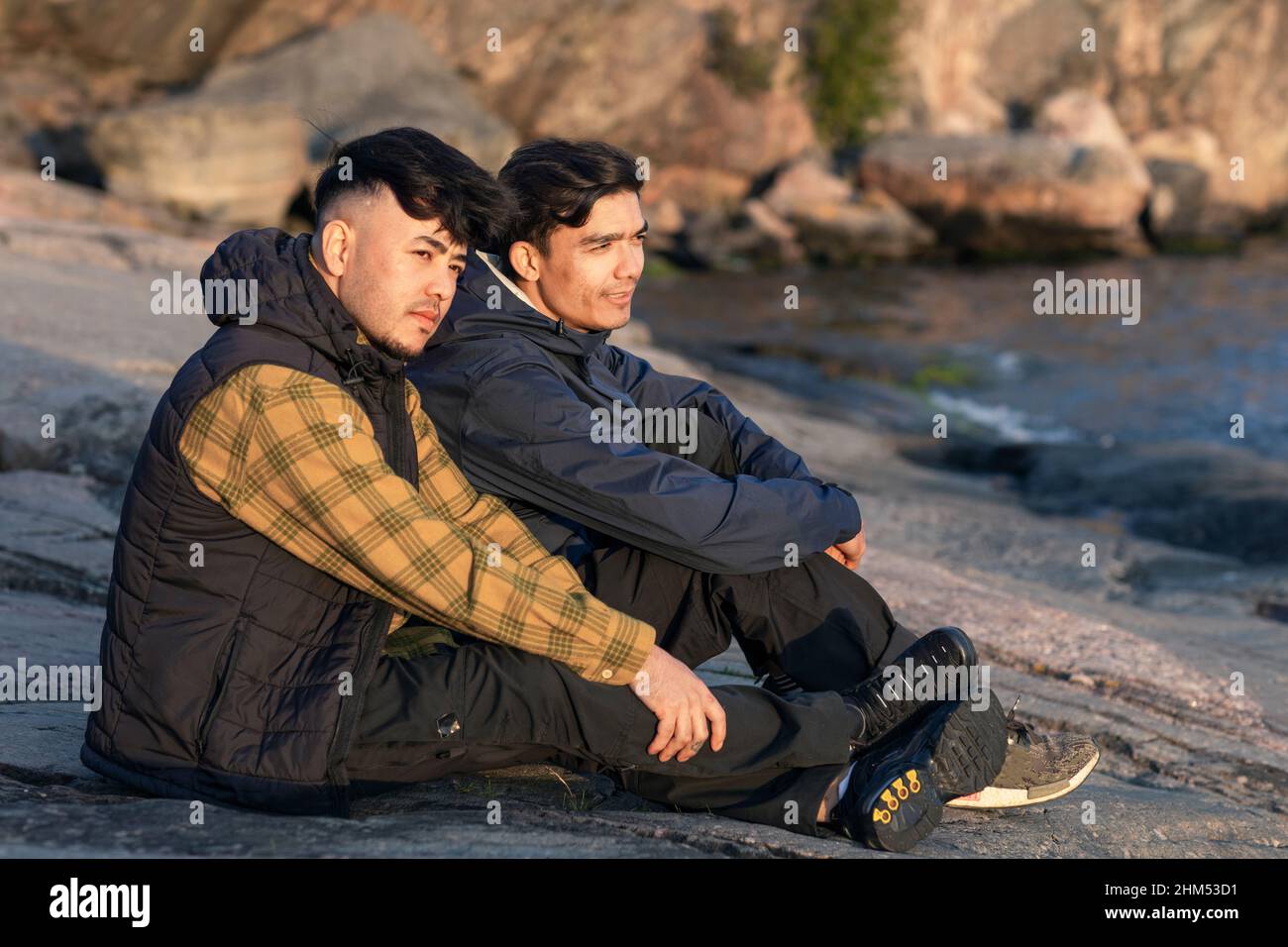 Male friends sitting at sea Stock Photo