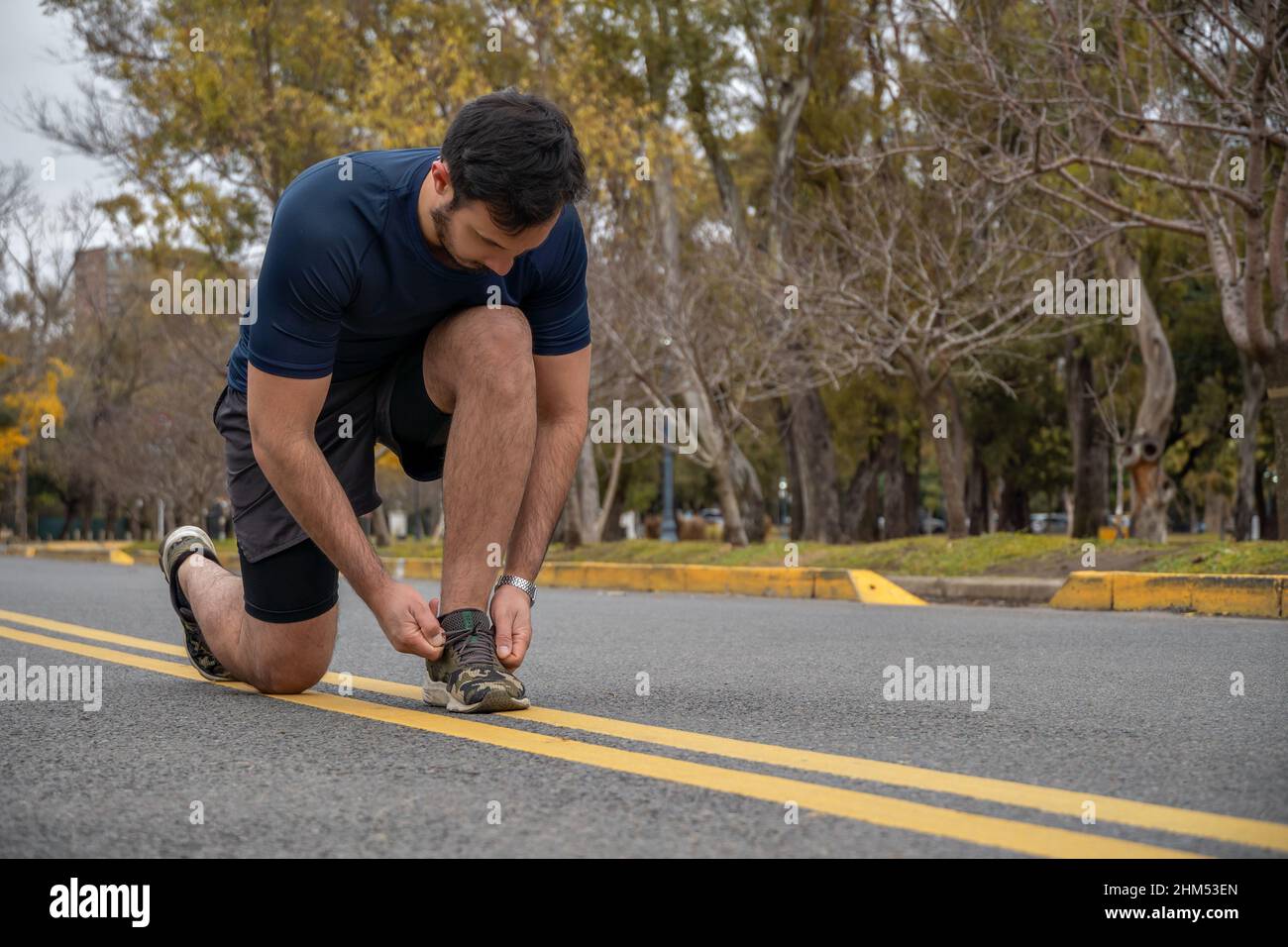 sporty man tying his shoelaces while exercising outdoors. Flush view. Healthy lifestyle concept Stock Photo