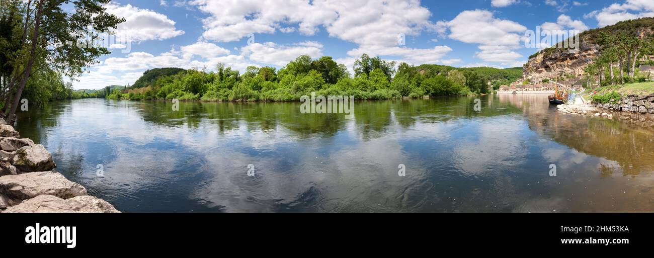 Panoramic of La Roque Gageac with cliffs and river boats in the summer sunshine and white clouds Dordogne France Stock Photo