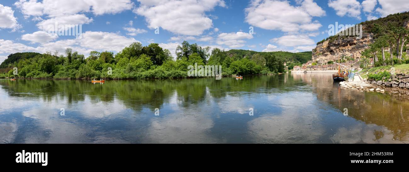 Panoramic of La Roque Gageac with pople canoeing ,cliffs and river boats in the summer sunshine and white clouds Dordogne France Stock Photo