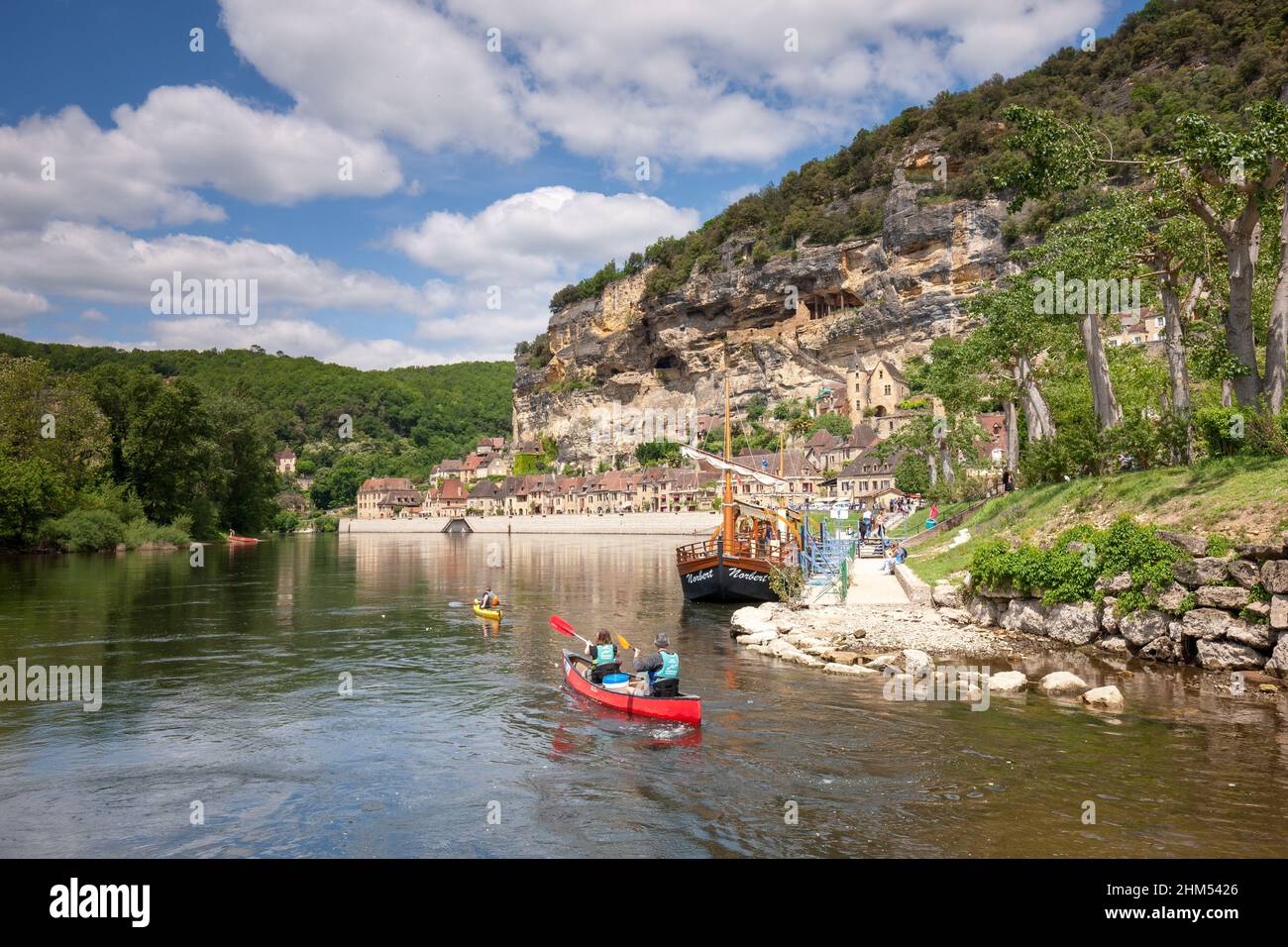La Roque Gageac with pople canoeing ,cliffs and river boats in the summer  sunshine and white clouds Dordogne France Stock Photo - Alamy