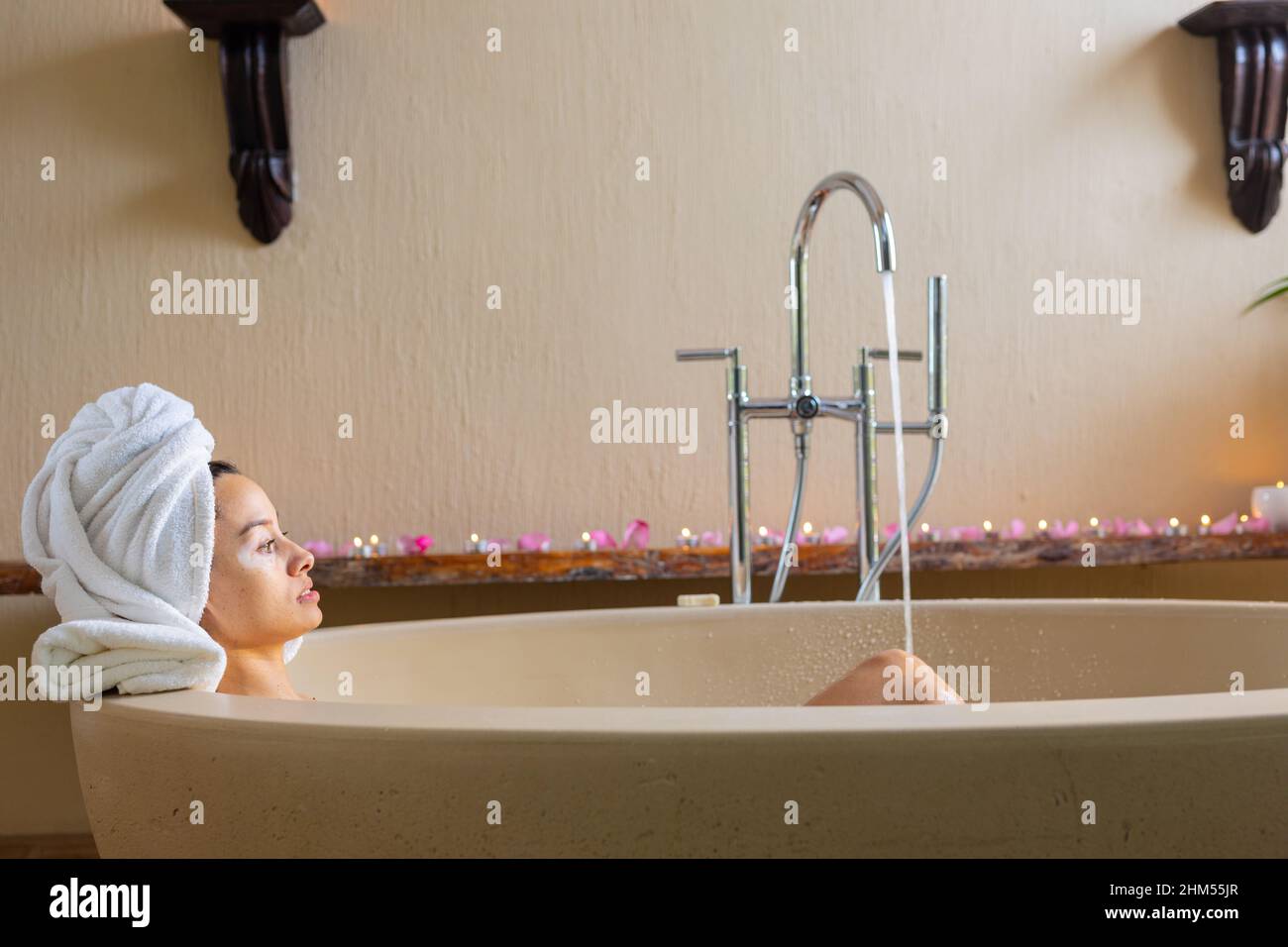 Side view of biracial young woman wearing towel on head sitting in
