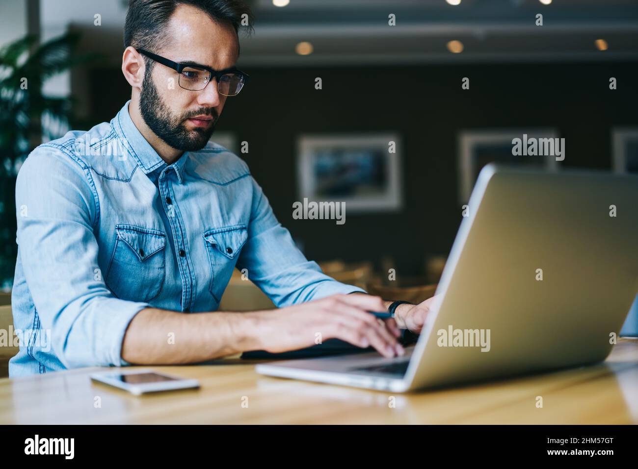 Focused male freelancer using laptop during workday Stock Photo