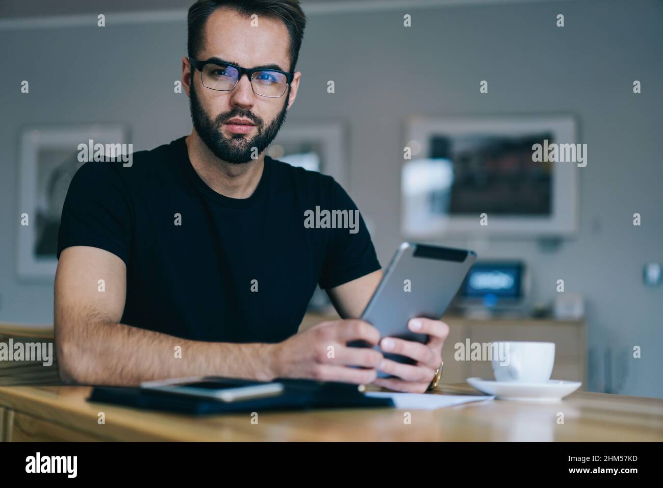 Serious freelancer using tablet in cafe Stock Photo