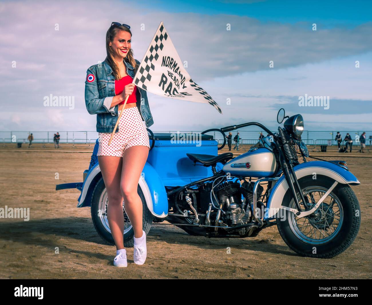 Ouistreham, France September 2021 A beautiful girl with a flag in her hand  is standing in front of an old motorcycle. Racing on the beach in Normandy  Stock Photo - Alamy