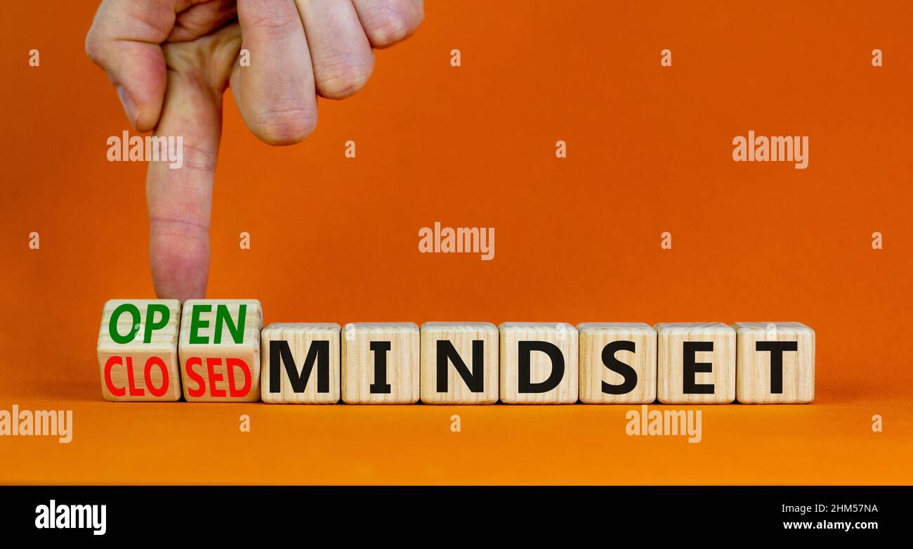 Open or closed mindset symbol. Businessman turns wooden cubes and changes concept words closed mindset to open mindset. Beautiful orange background co Stock Photo