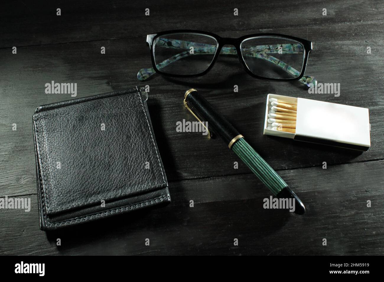 Closeup of a man's personal items, wallet, fountain pen, glasses and matchbox Stock Photo