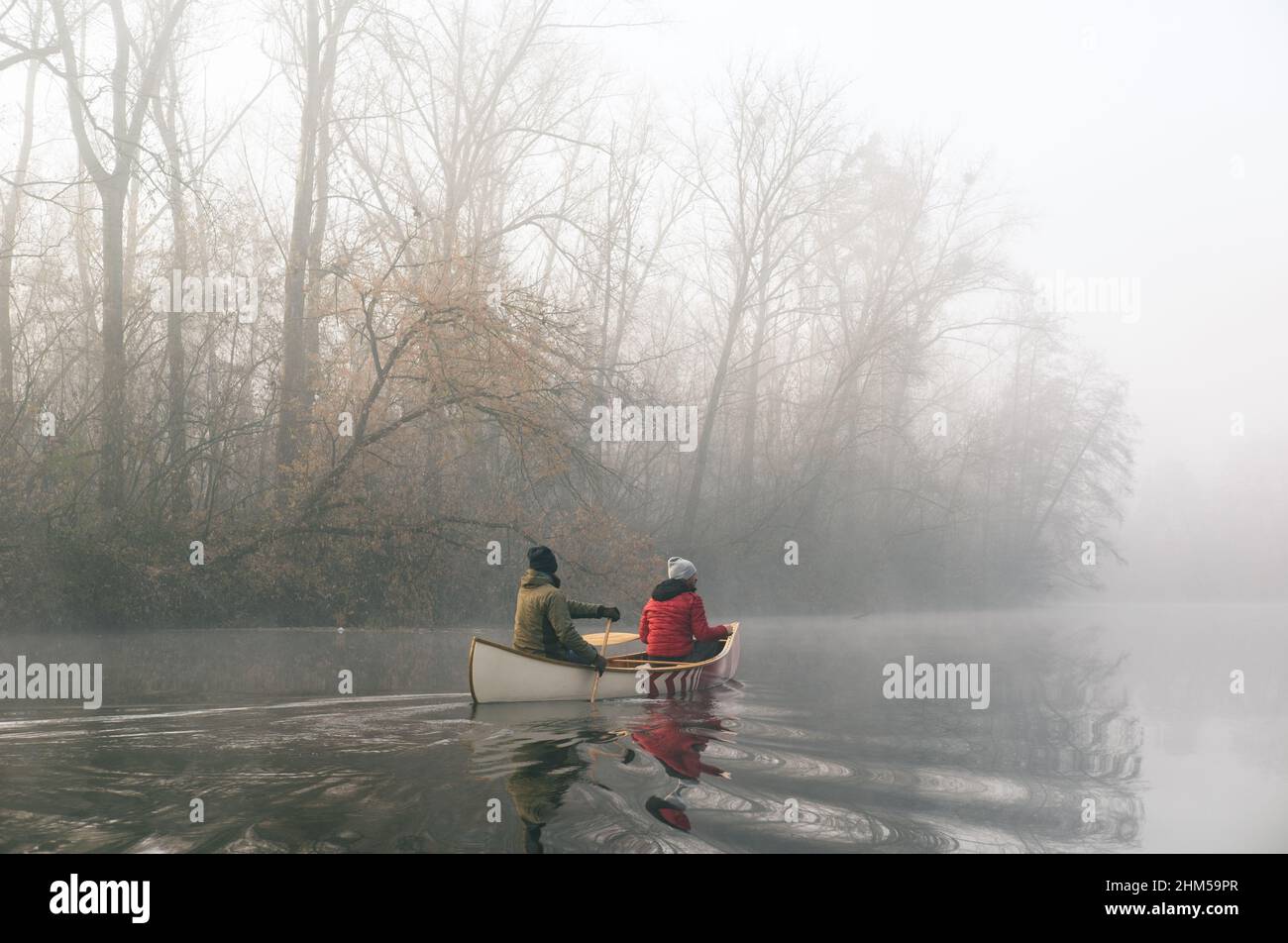 Two men paddling in a wooden canoe on a misty river Stock Photo - Alamy