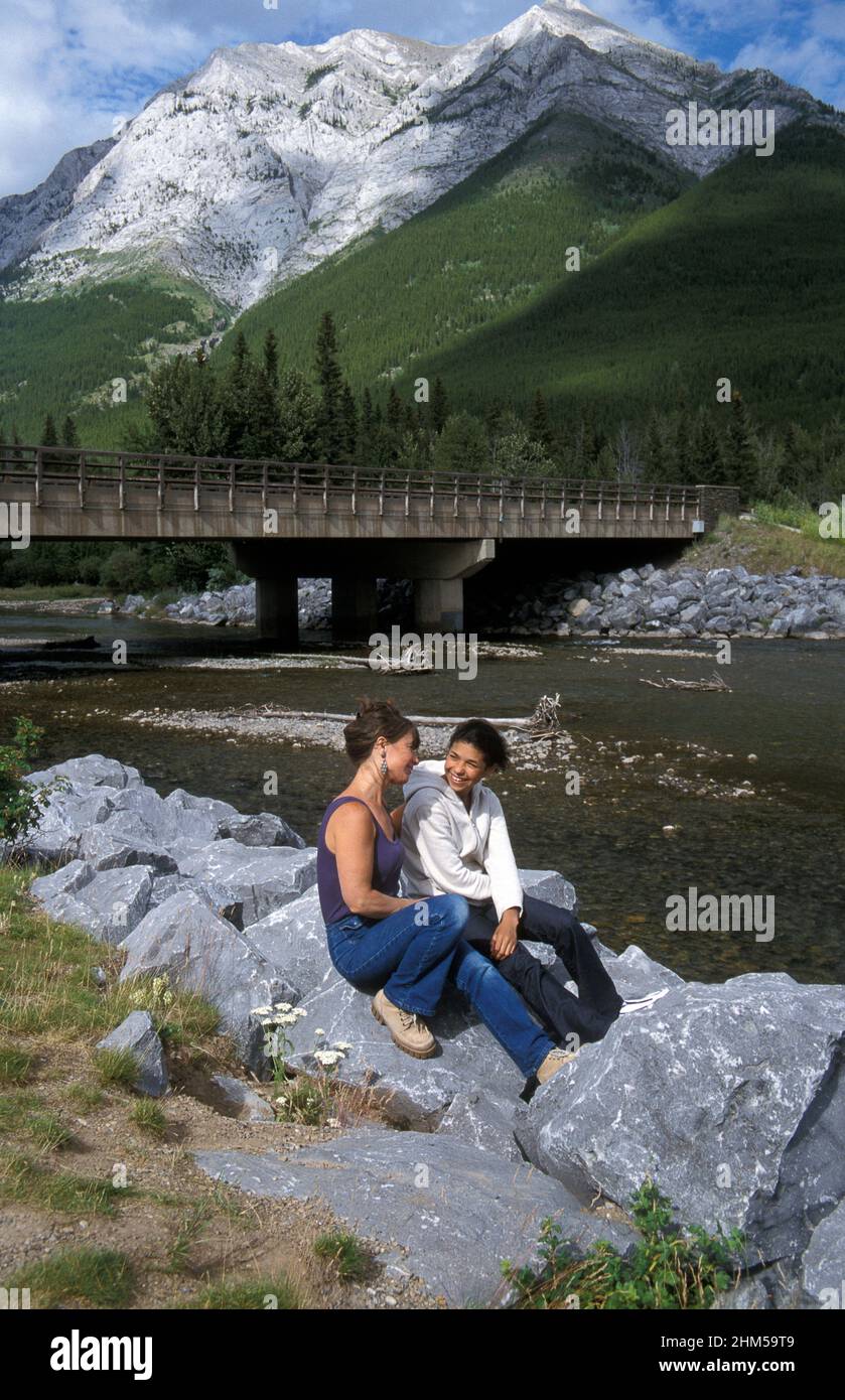 adult and young girl sitting by Kananaskis River, Alberta, Canada, North America Stock Photo