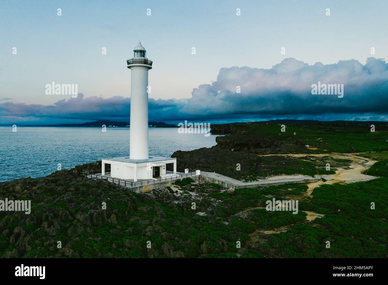 White lighthouse on ocean cliff coastline clouds captured by drone Stock Photo