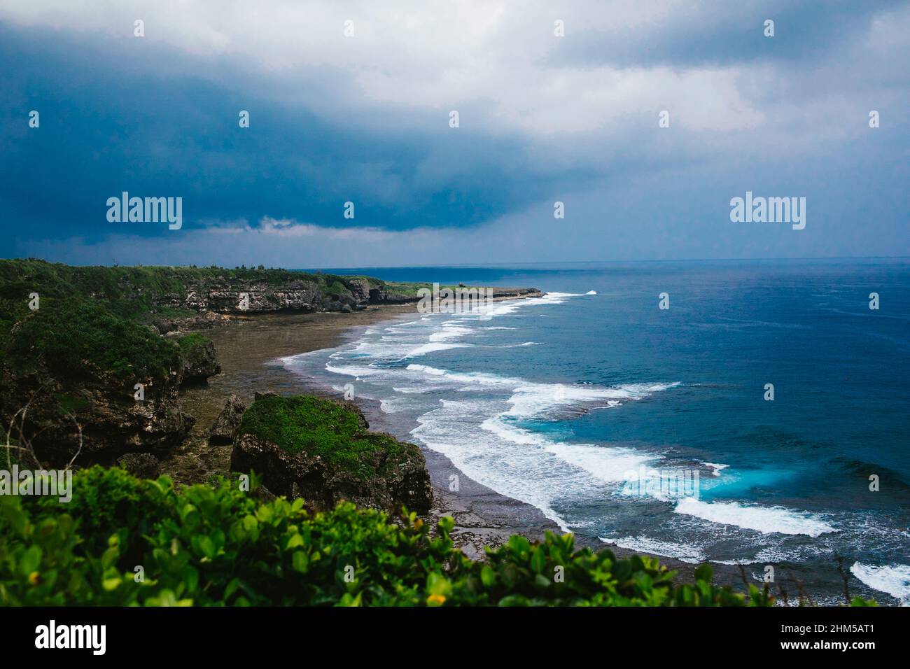 Storm rolls in over ocean and tropical island with waves and clouds Stock Photo